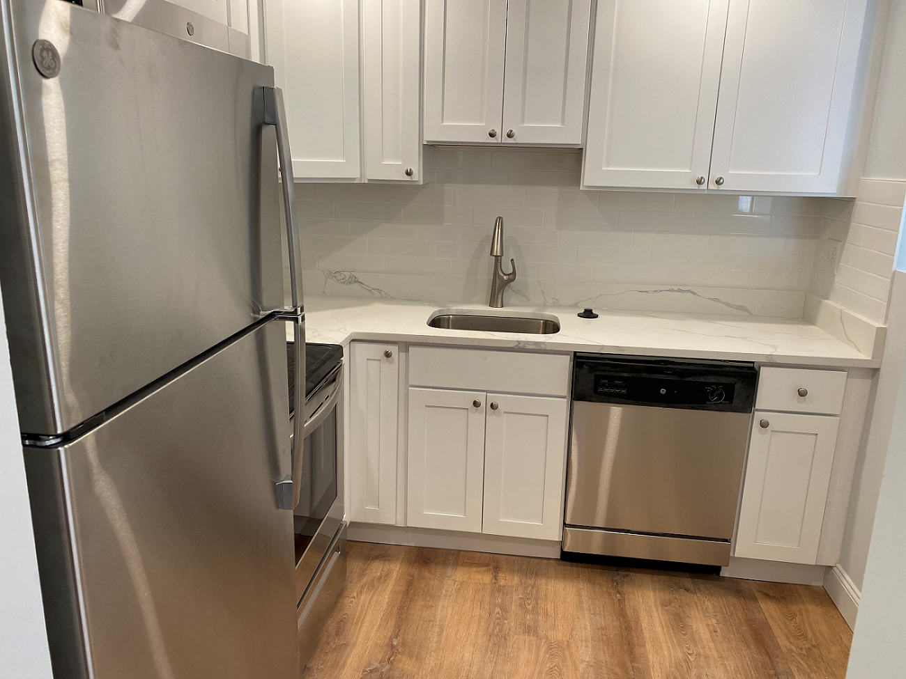 a small kitchen with white cabinets and stainless steel appliances
